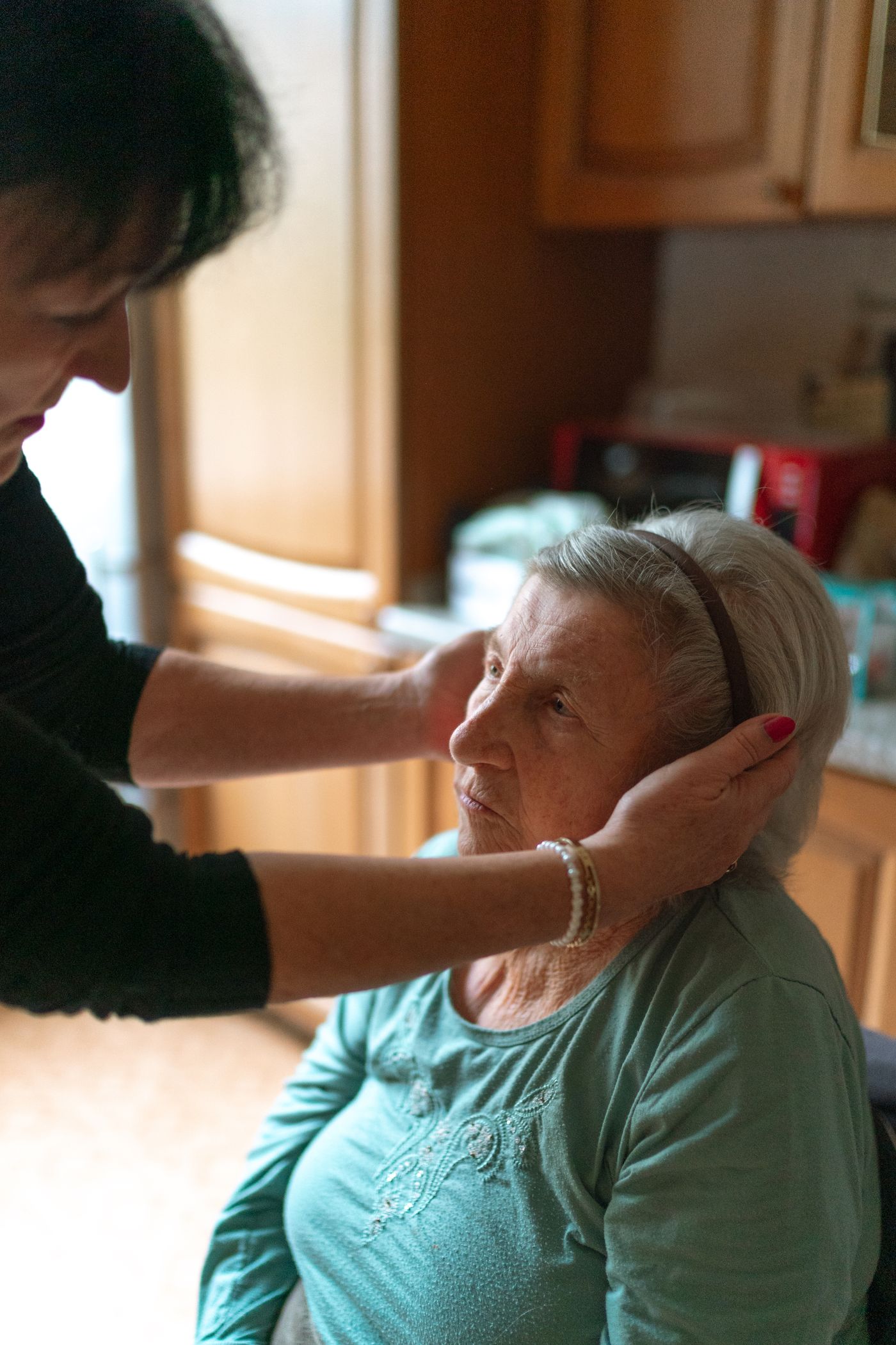 A caregiver gently assisting an older woman at home
